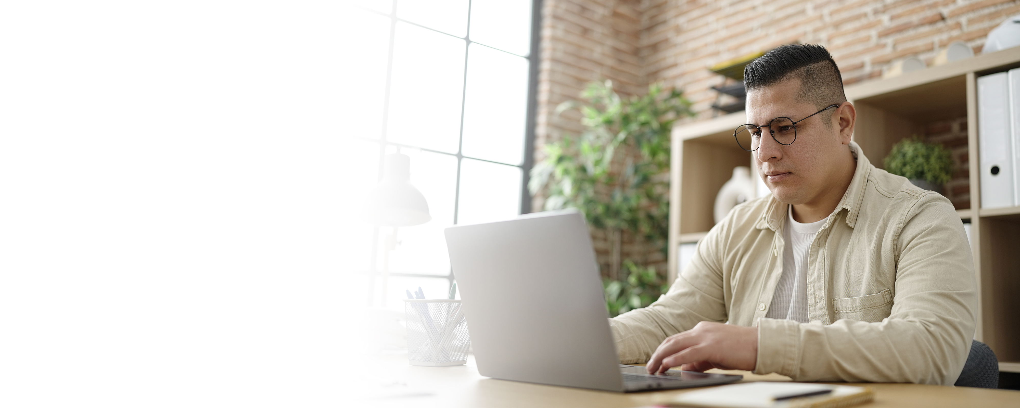 Adult Latinx man wearing glasses and typing on laptop