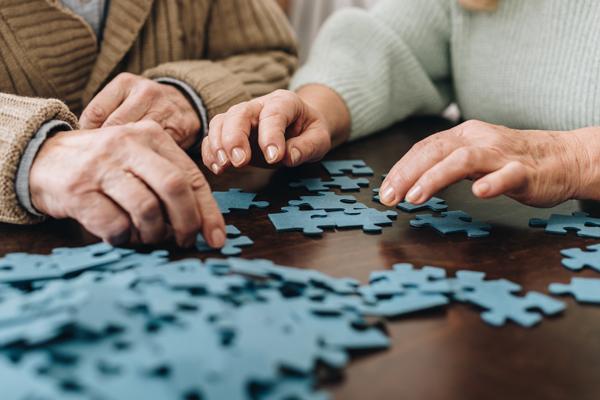 Close up of two seniors' hands building a puzzle